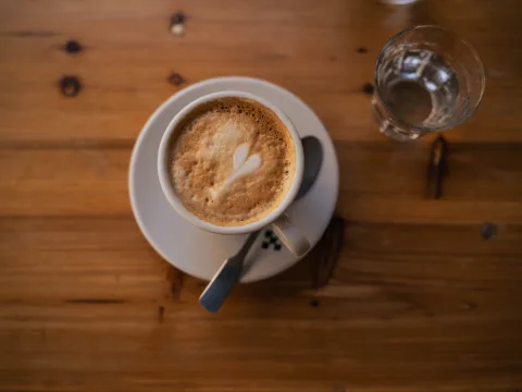 Un tavolo di legno con una tazza di caffè macchiato.