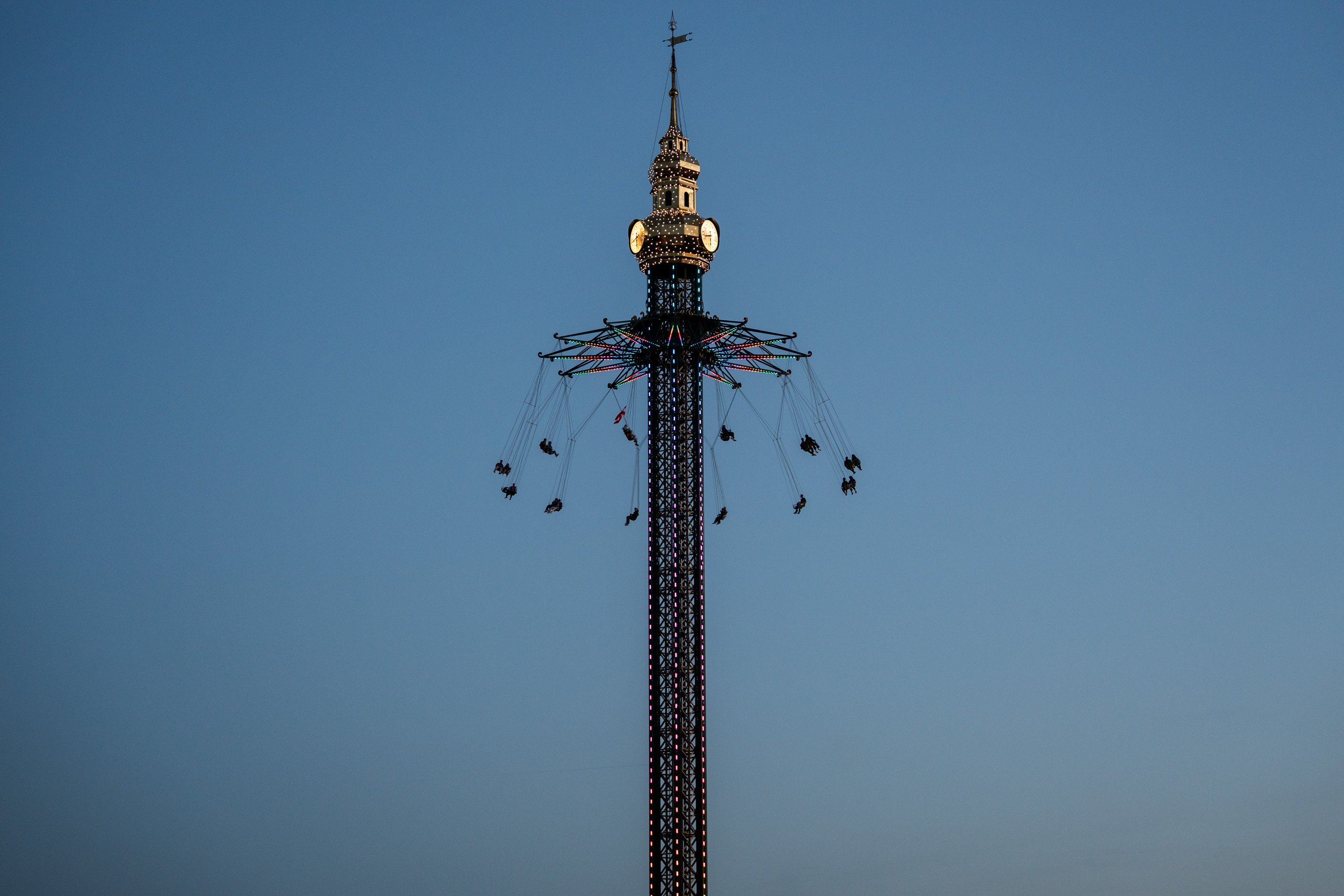 La torre del Prater illuminata con la giostra a catene in movimento si staglia sul cielo blu della sera nel Prater di Vienna.