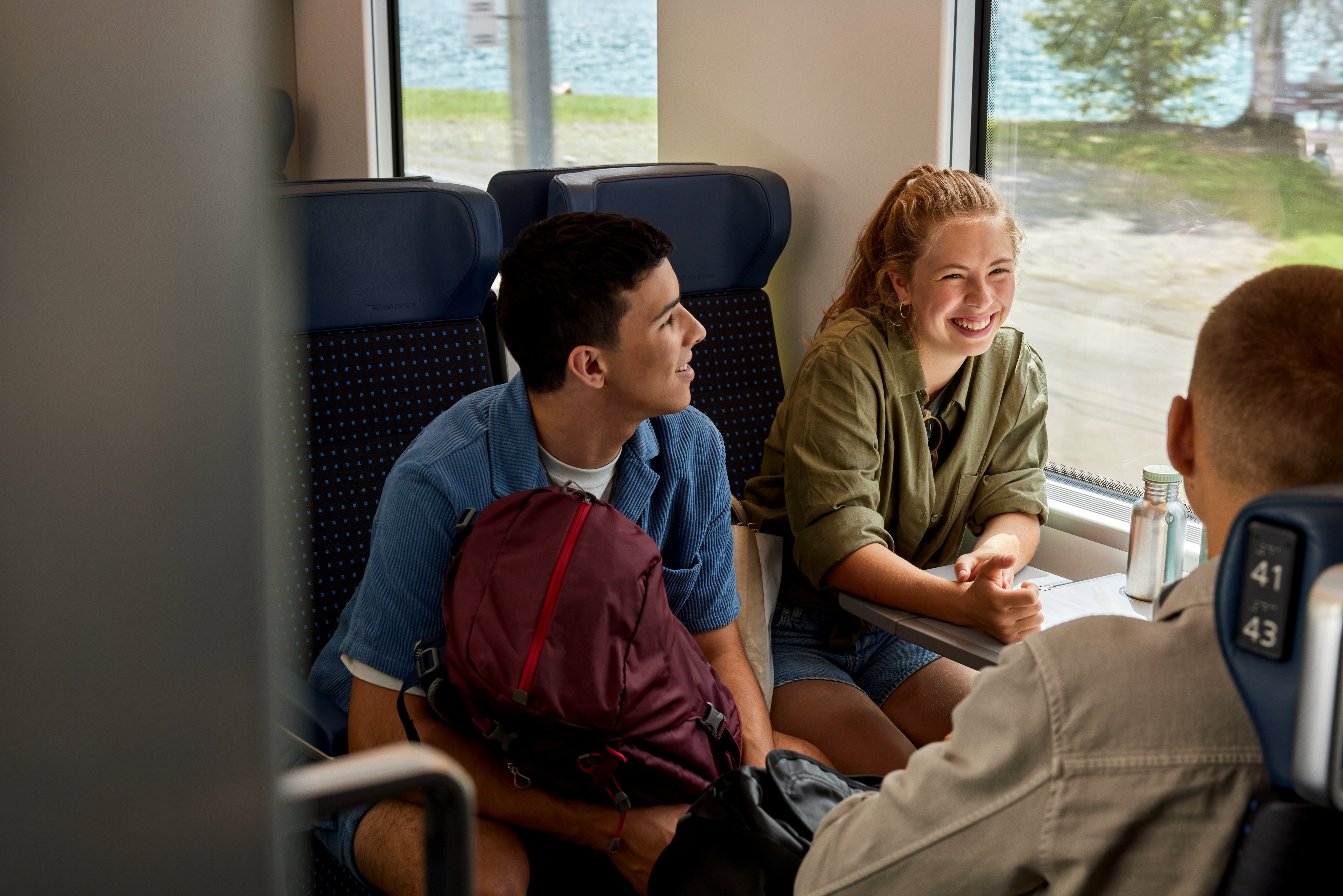 Un gruppo di persone, tra cui una donna che ride, è seduto su un treno.