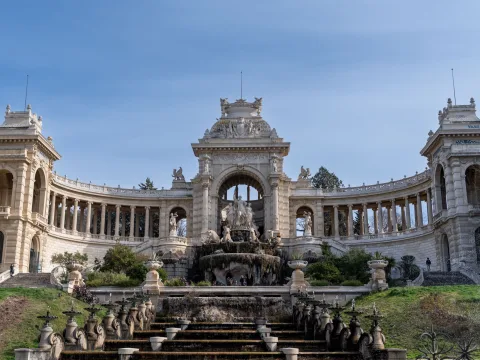 Vue du majestueux Palais Longchamp à Marseille, avec son impressionnante fontaine, ses élégantes colonnades et ses sculptures, sous un beau ciel bleu.