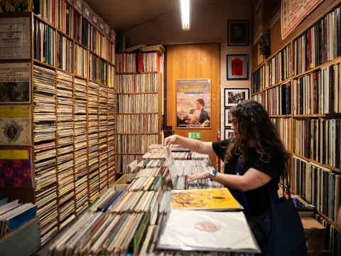 Una donna cerca tra i vinili del negozio di dischi viennese Alt & Neu circondata da scaffali pieni di CD e LP fino al soffitto.