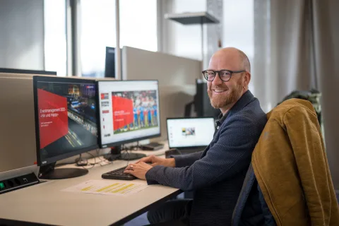 Florian Kurt, assis à son poste de travail, regarde la caméra.