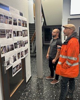 Zwei Mitarbeitende schauen an eine Pinnwand