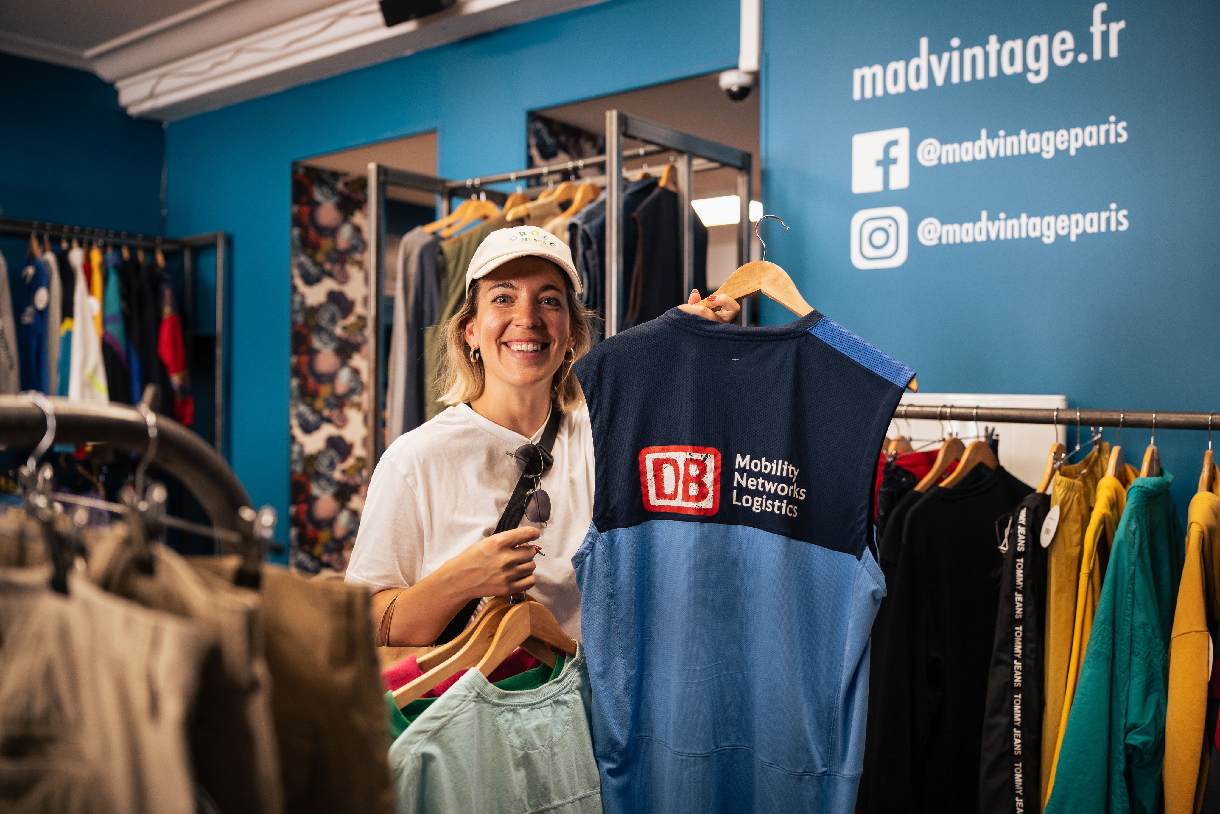 Una donna tiene in mano una T-shirt della Deutsche Bahn in un negozio vintage. 