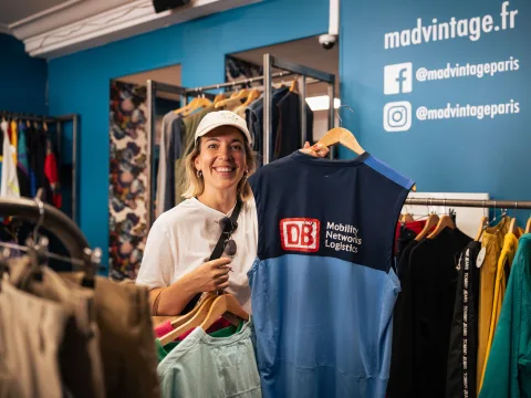 Una donna tiene in mano una T-shirt della Deutsche Bahn in un negozio vintage.