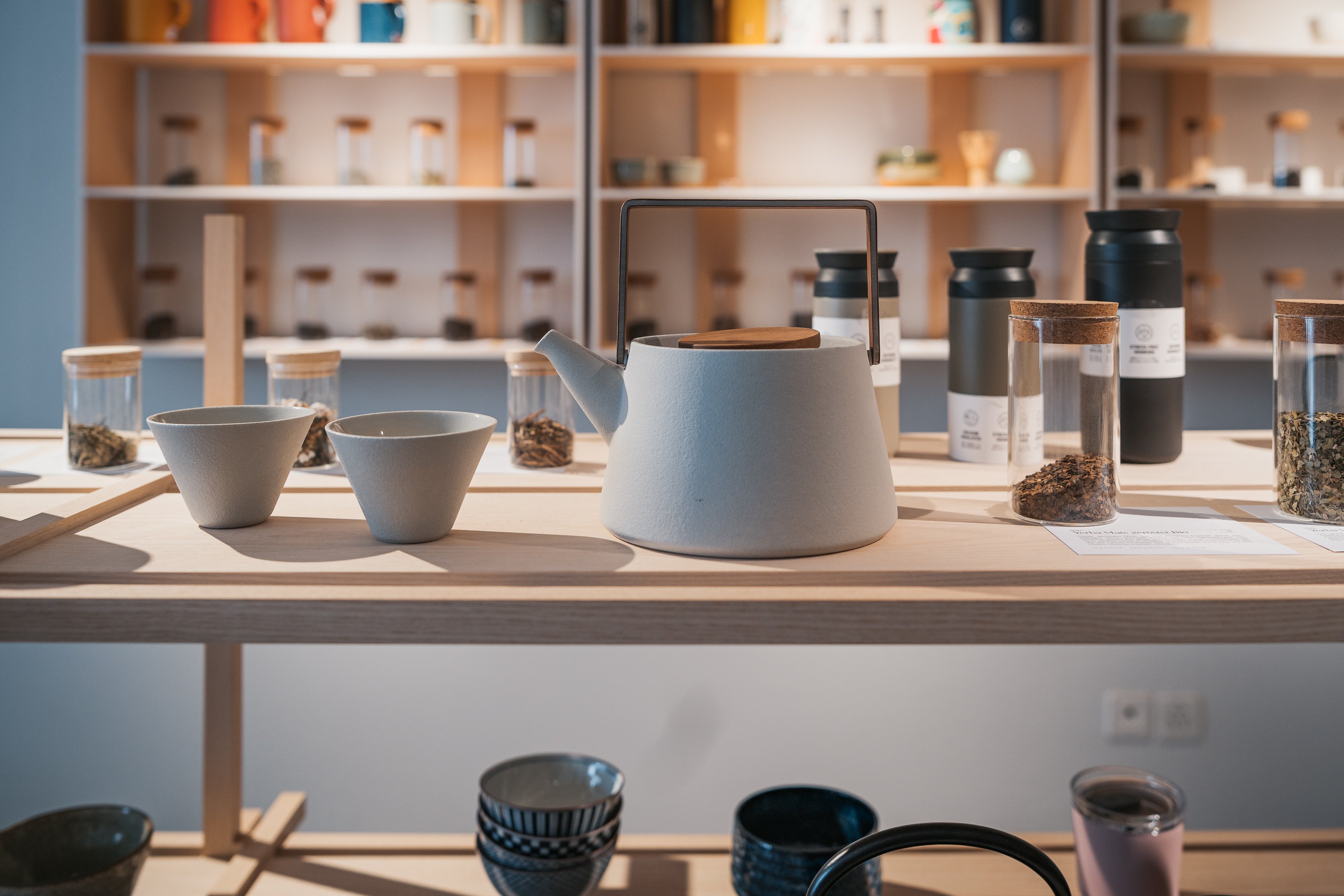 Teiera e tazze nel Teeladen di Coira, con varie miscele di tè sullo sfondo.