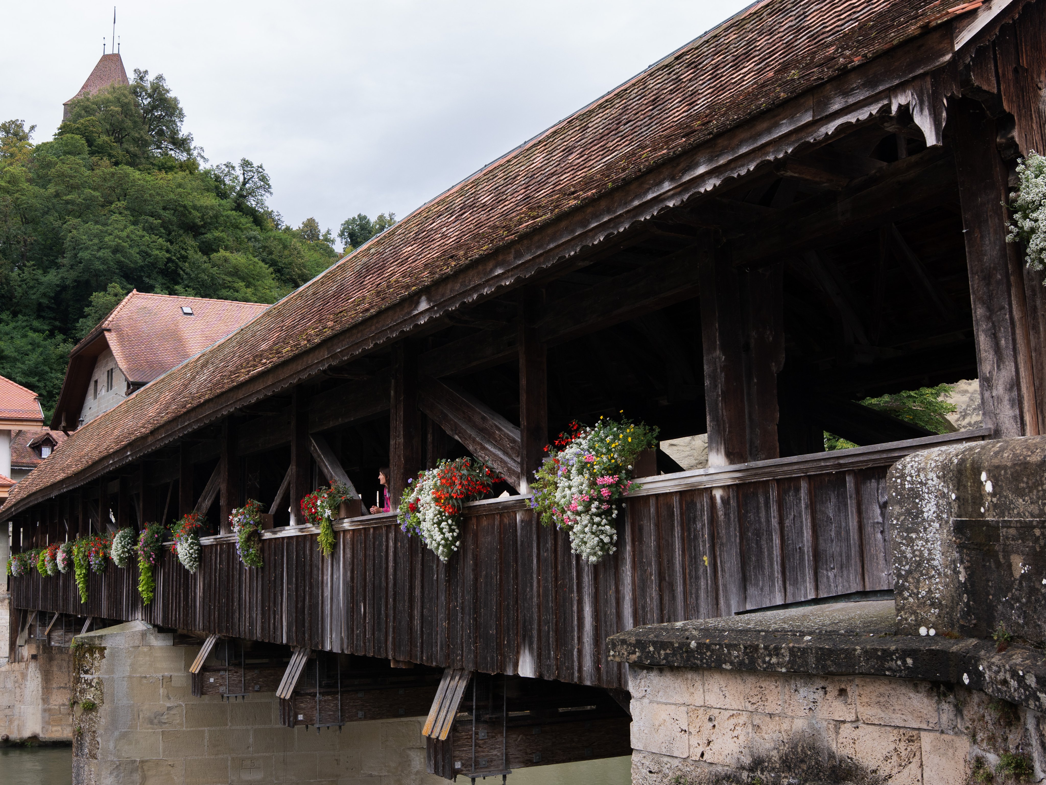 Un pont en bois avec un toit, décoré de fleurs.