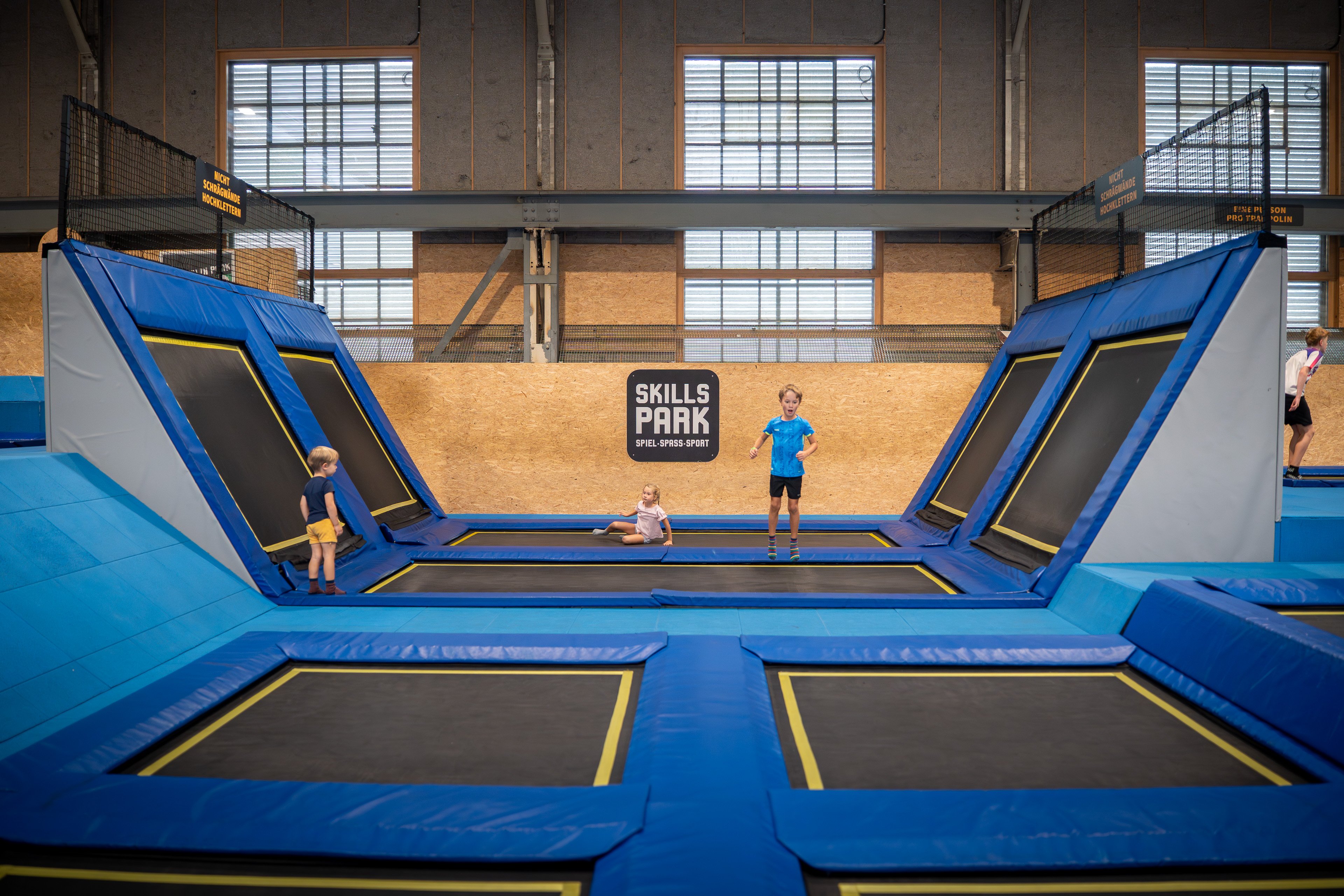 Drei Kinder auf dem Trampolin im Skills Park. 