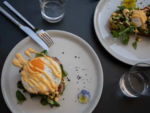 Avocado-Toast und die Savoury Pancakes EK schön serviert uf zwei Tellern.
