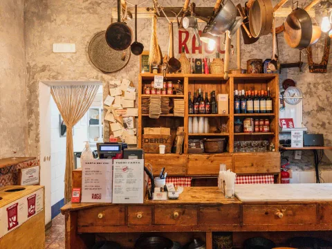 Rustic bistro with wooden furniture, shelves full of bottles and decoration.