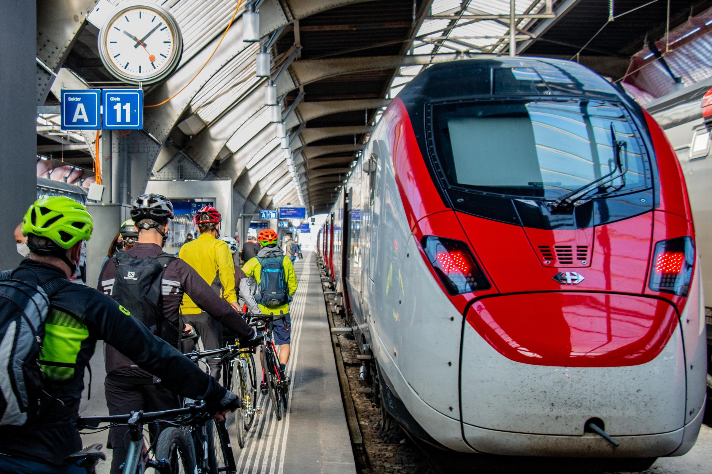 Un groupe de voyageurs poussant des vélos le long d’un train à quai.