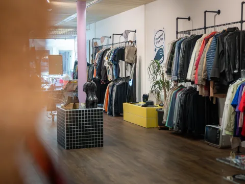 Eine Ladenfläche mit üppig gefüllten Kleiderstangen und dekorativen Elementen.