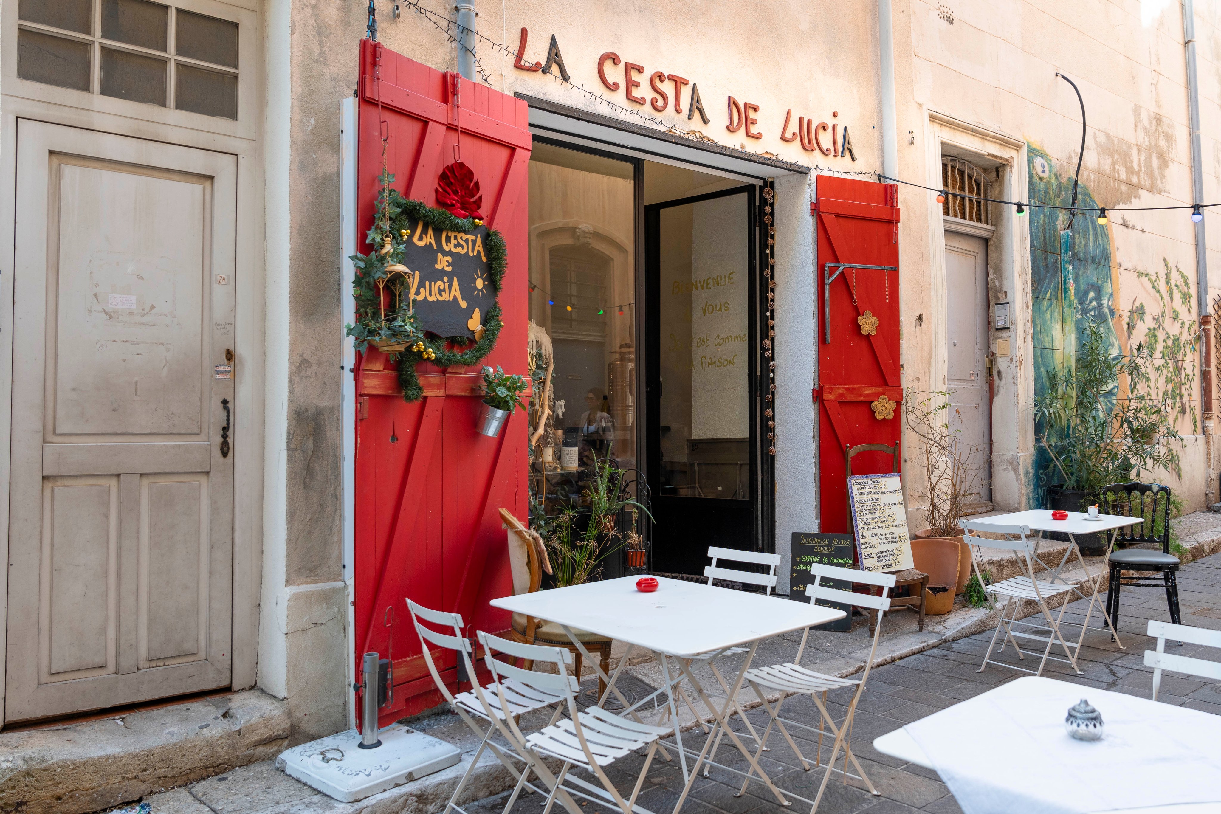 Le restaurant La Cesta de Lucía dans une rue calme du Panier, à Marseille, avec sa terrasse, sa porte à la décoration originale et ses lumières multicolores.