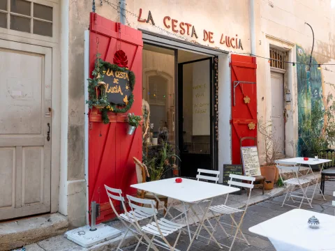 Le restaurant La Cesta de Lucía dans une rue calme du Panier, à Marseille, avec sa terrasse, sa porte à la décoration originale et ses lumières multicolores.