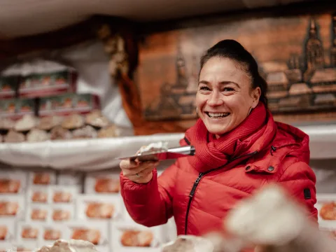 Verkäuferin verkauft Christstollen aus einem Stand am Münchner Christkindlmarkt.