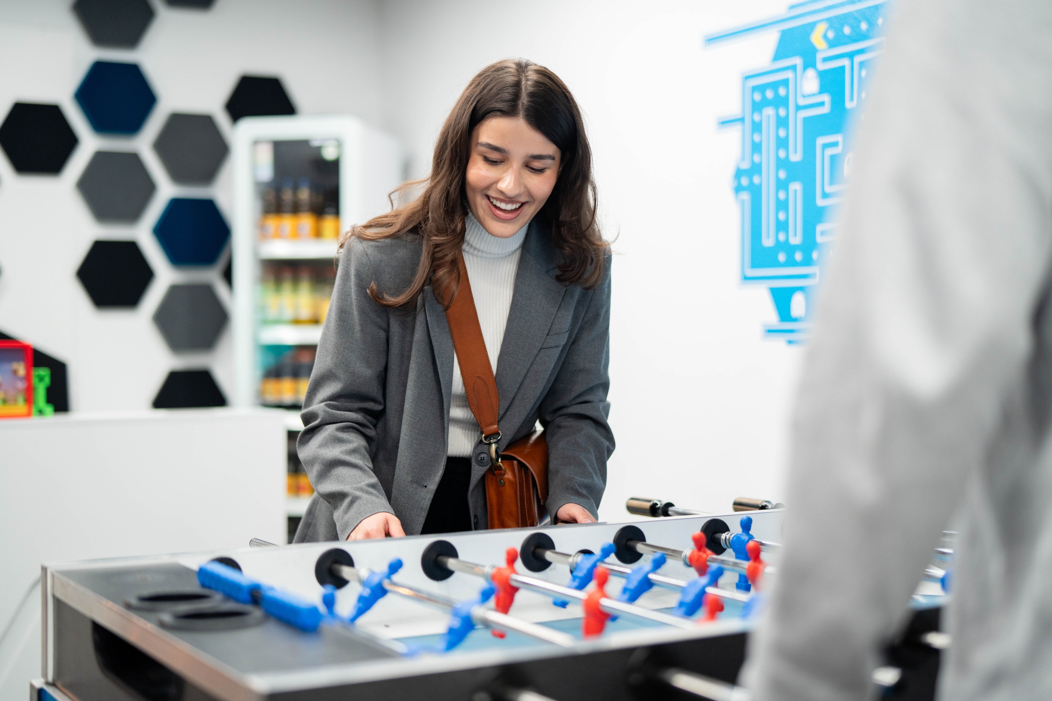 A woman plays table football and looks cheerful.
