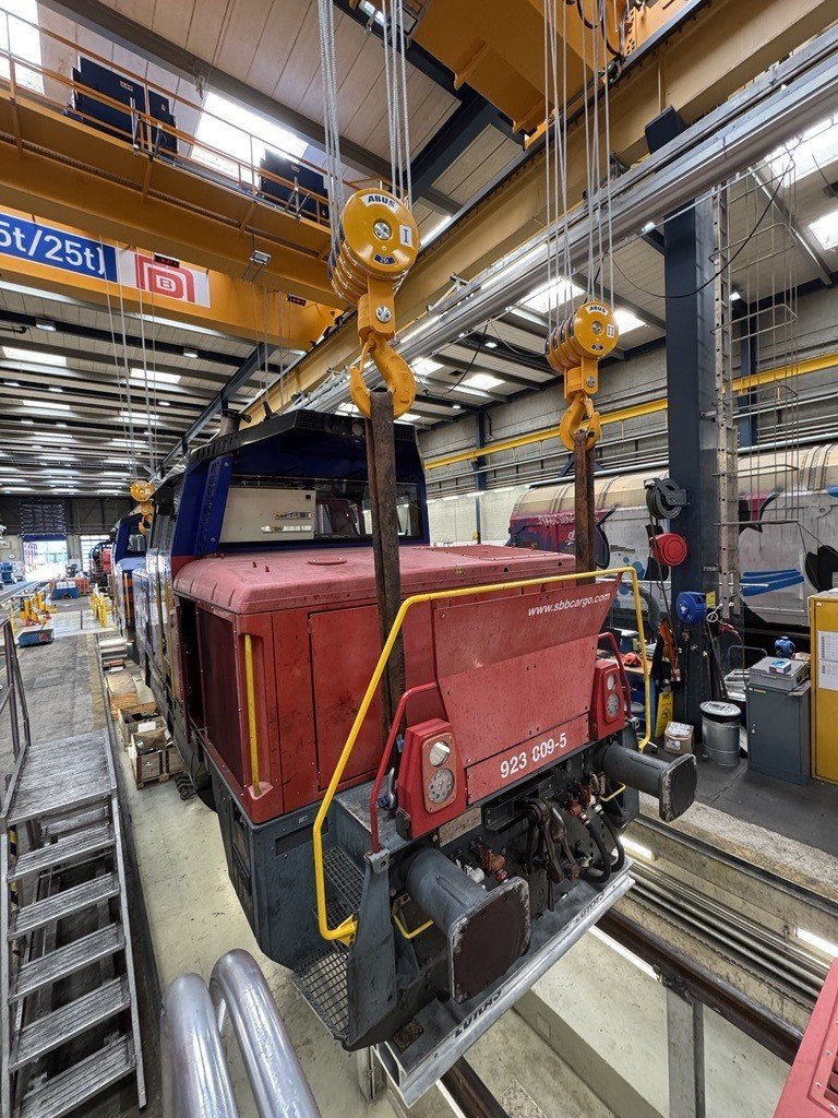 La nouvelle grue maintient solidement une locomotive de manœuvre Eem 923 par des élingues, avant de la soulever.