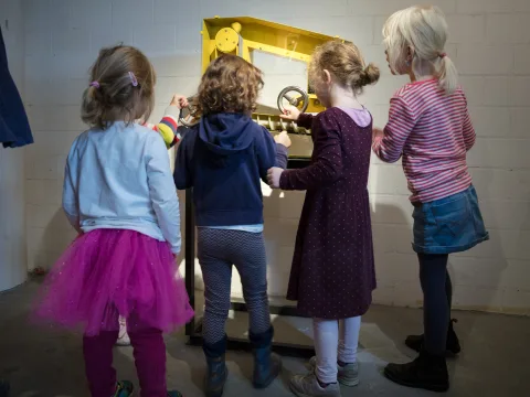 Vier Kinder stehen vor einer alten Getreidemühle.