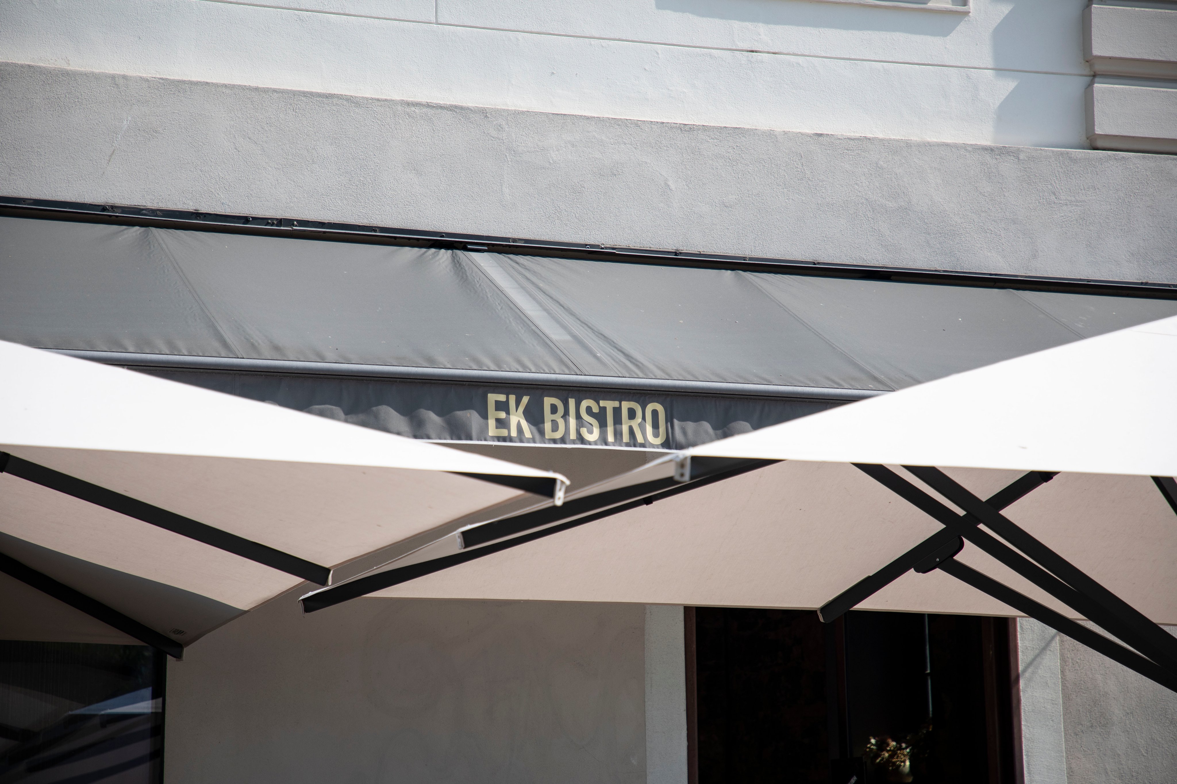 Offene Terrassenschirme und die Restaurantbeschriftung Ek Bistro.