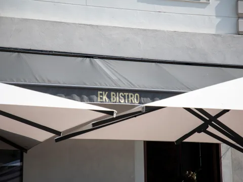 Offene Terrassenschirme und die Restaurantbeschriftung Ek Bistro.