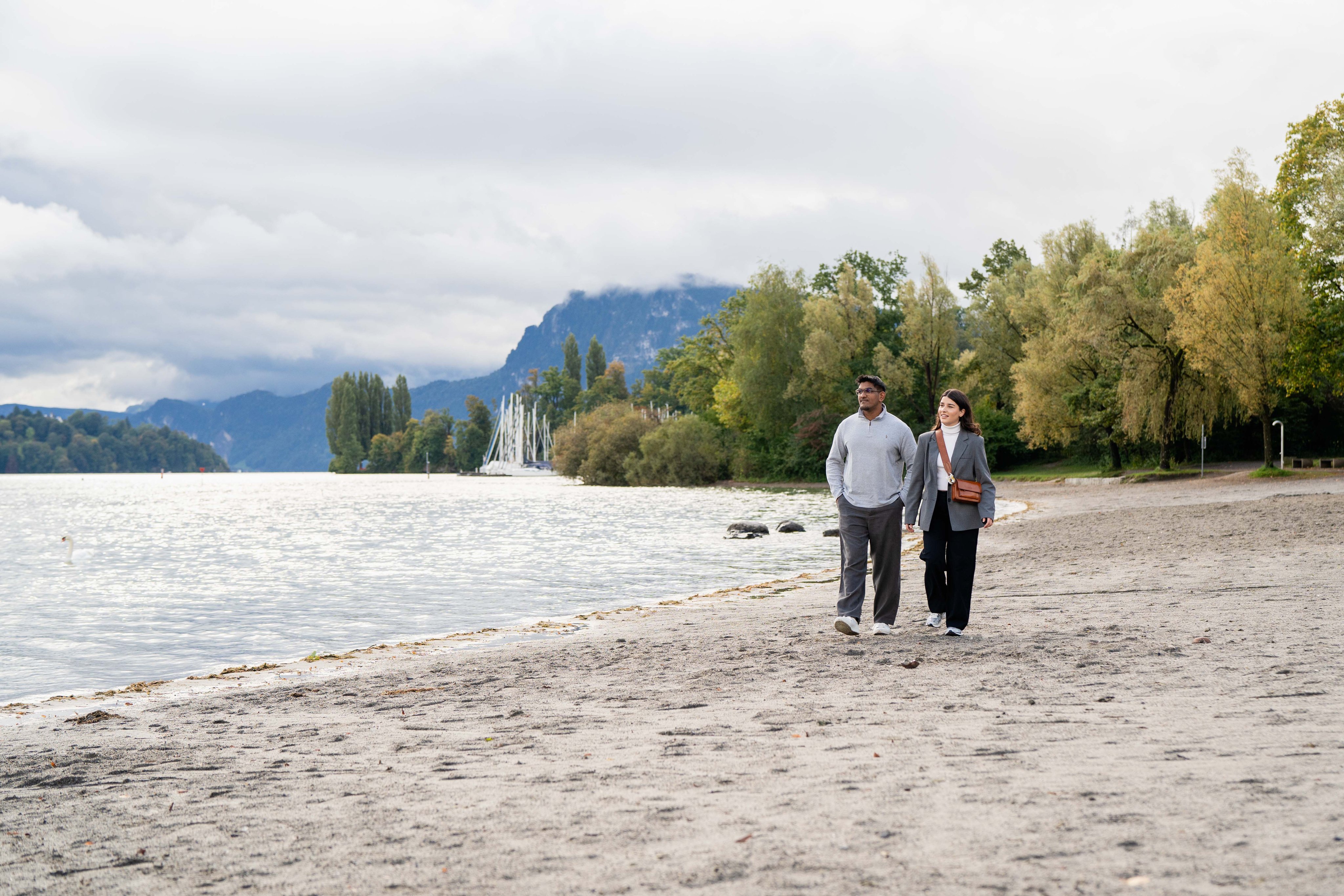 A man and a woman walking on the beach on Lake Lucerne.
