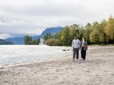 A man and a woman walking on the beach on Lake Lucerne.