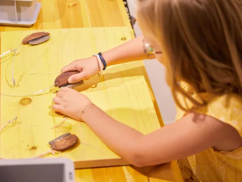 Kind hantiert im Museum Kulturama mit Steinzeit-Werkzeug.