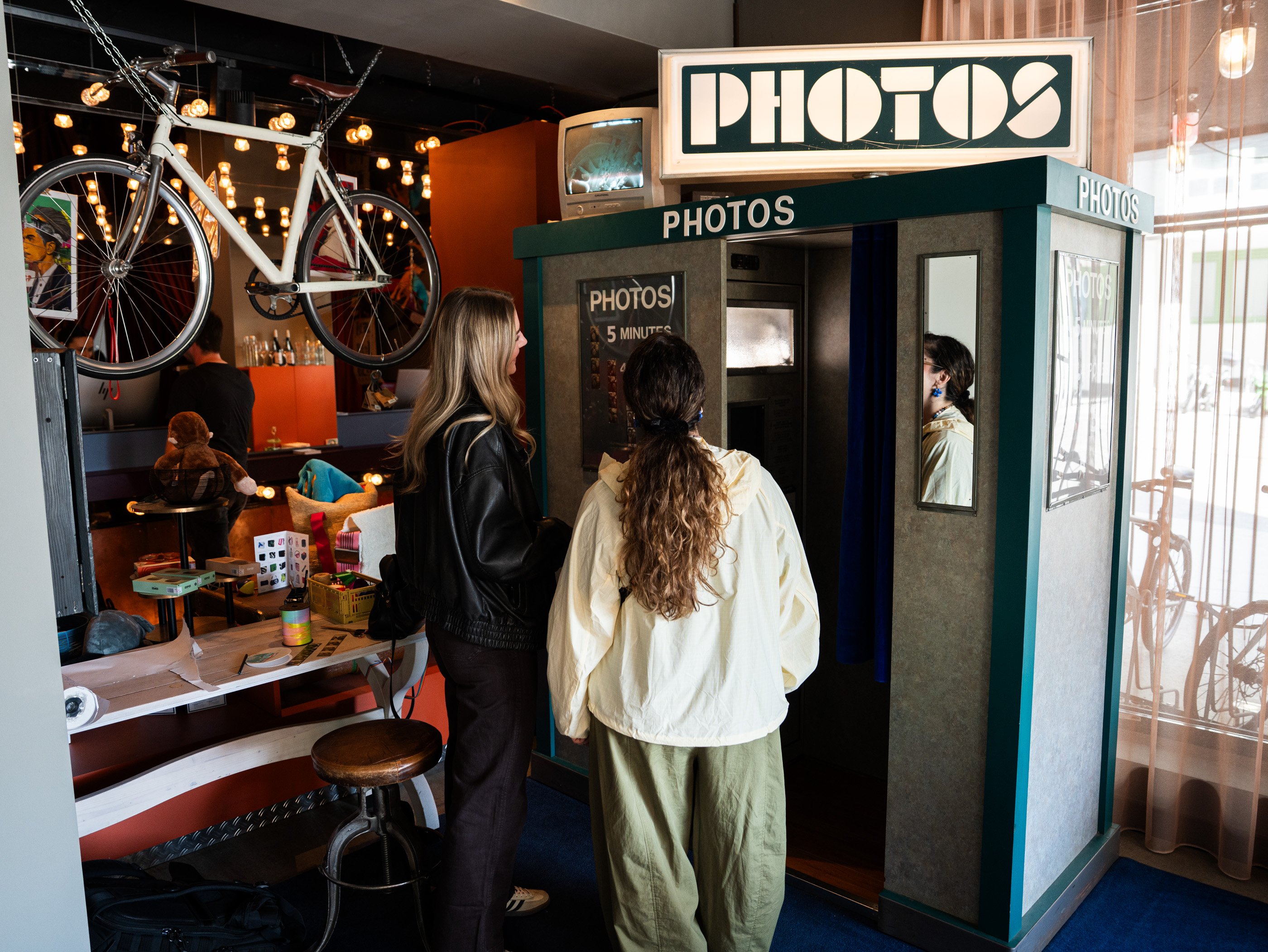 Due donne sono in piedi davanti a una delle cabine per fototessere nel colorato 25hours Hotel a Vienna.