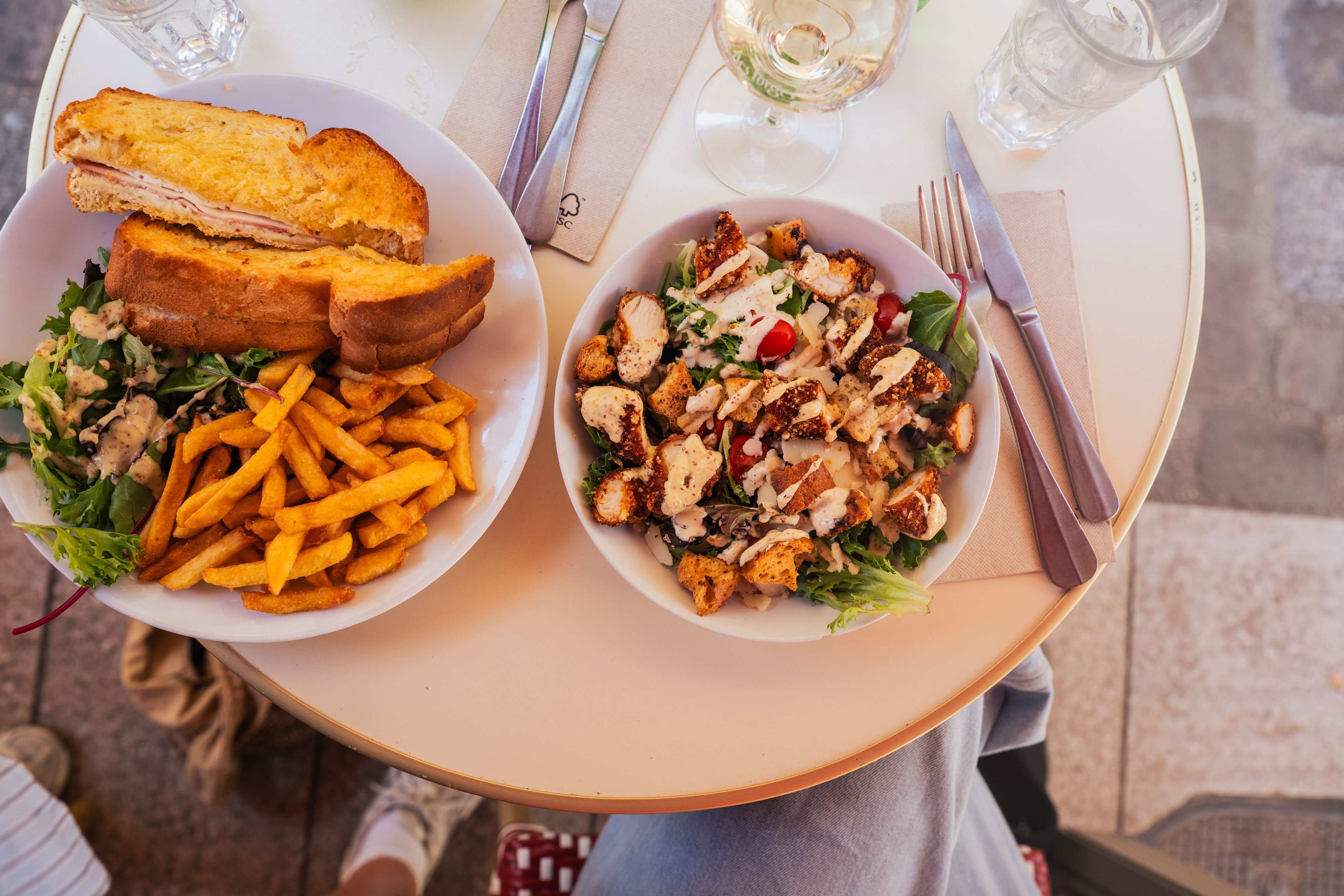 Un tavolo con un croque-monsieur tagliato e una croccante insalata Caesar.