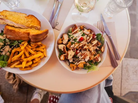 Un tavolo con un croque-monsieur tagliato e una croccante insalata Caesar.