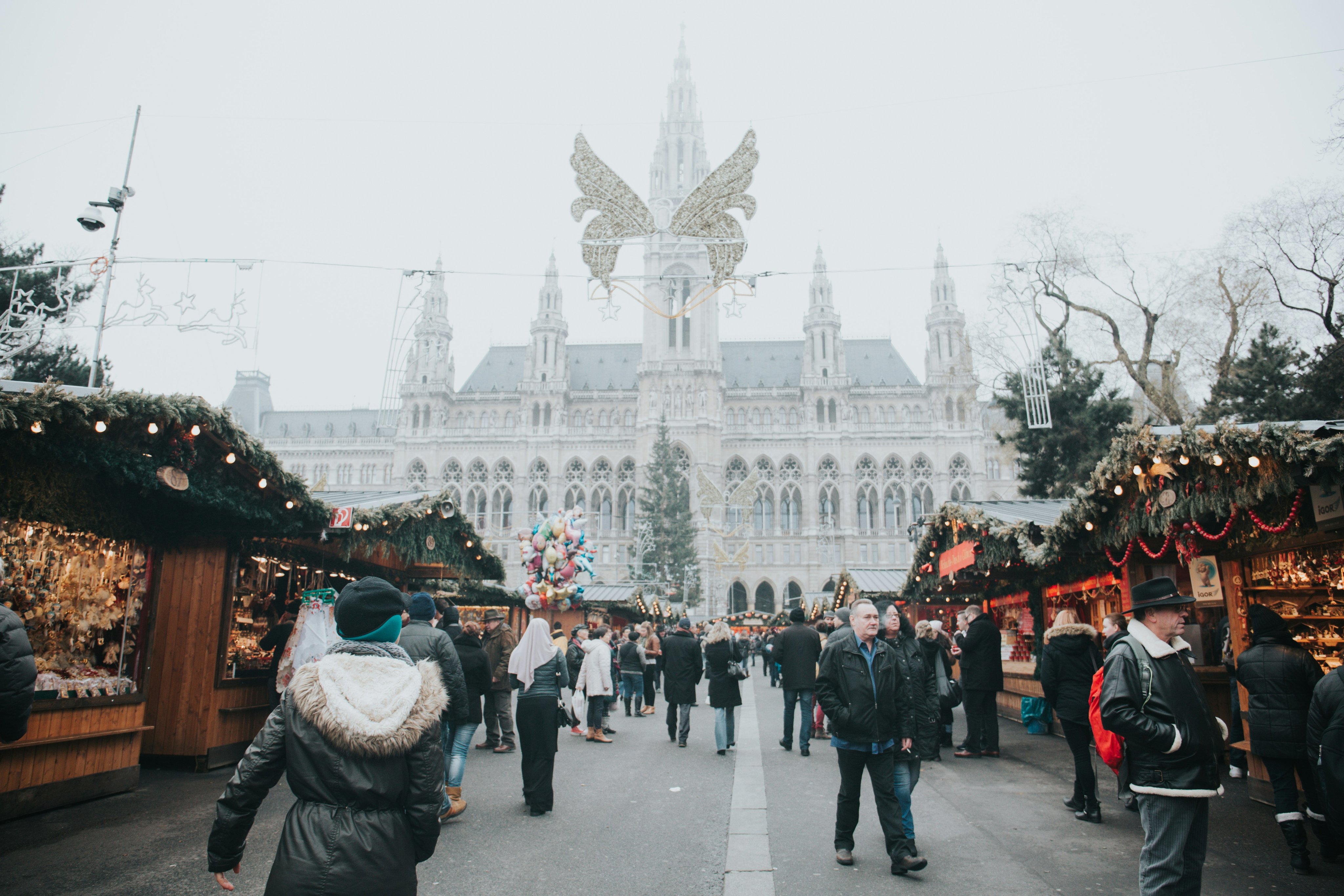 Menschen spazieren über einen festlich beleuchteten Weihnachtsmarkt mit bunten Ständen und winterlicher Atmosphäre. 