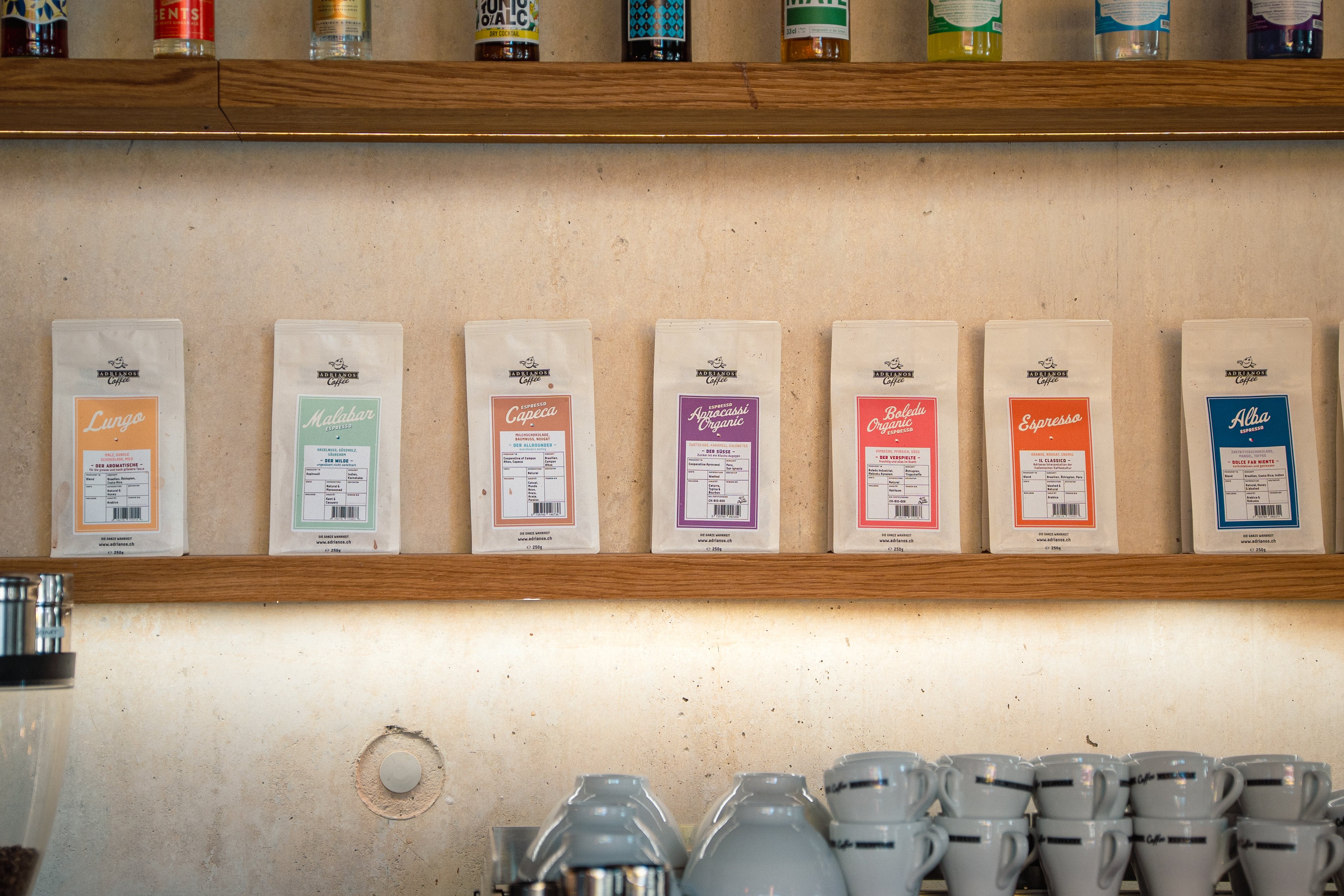 Su una mensola di legno sono allineate diverse confezioni di caffè.