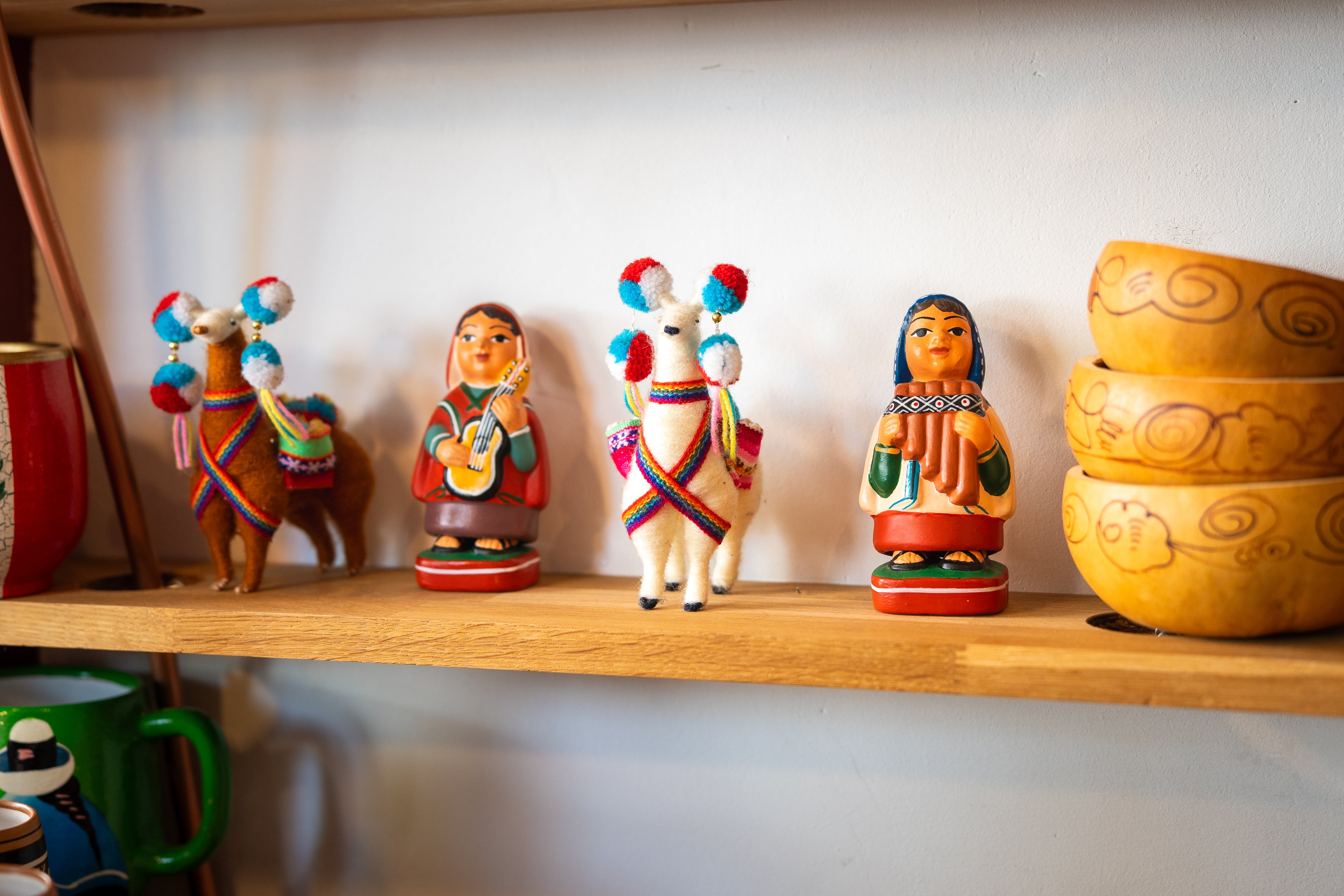 Su una mensola si trovano tre ciotole e diverse figure decorative: donne in abiti tradizionali e due lama.