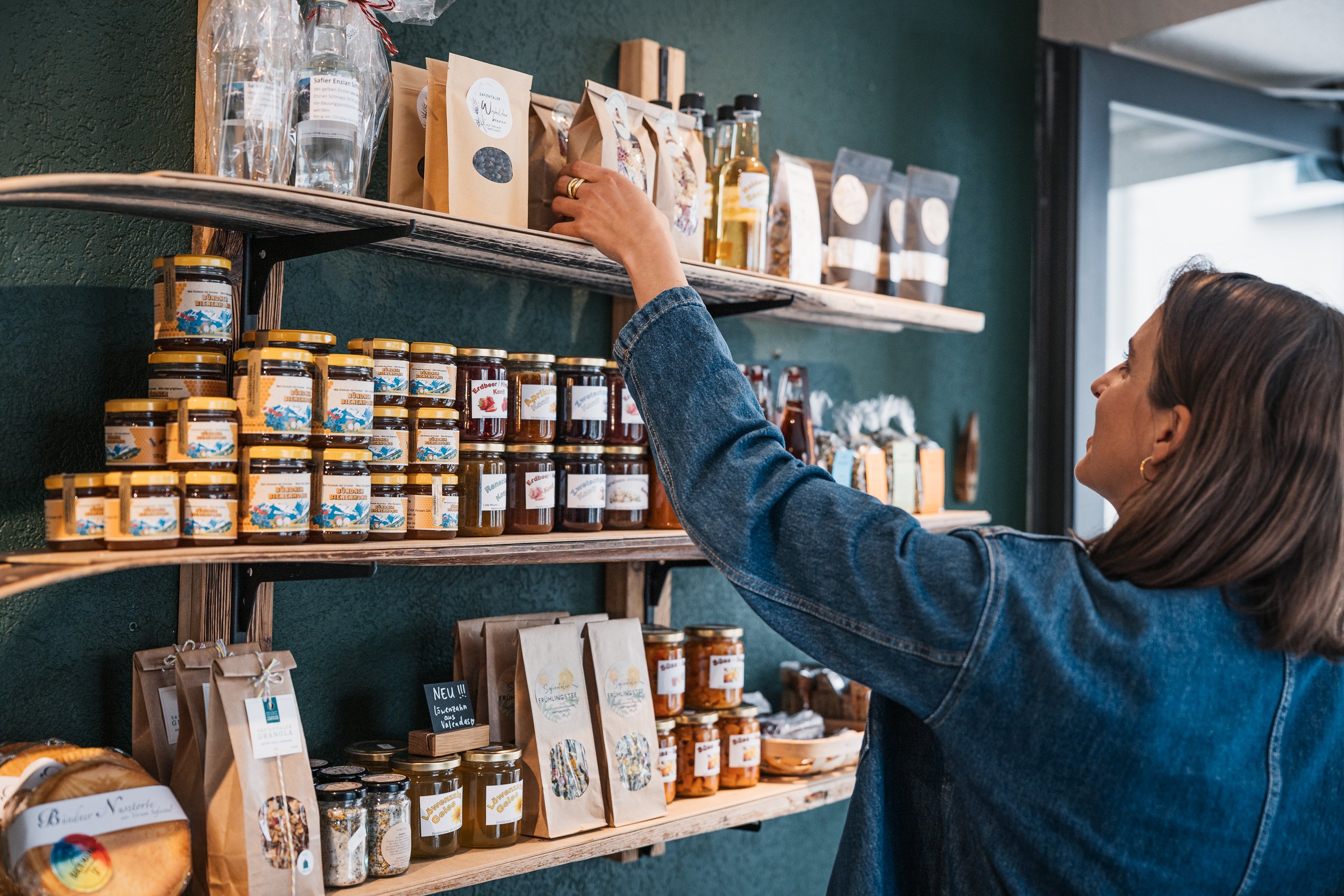 Una donna prende una miscela di tè da un ripiano del bistrò Botschaft Safiental.