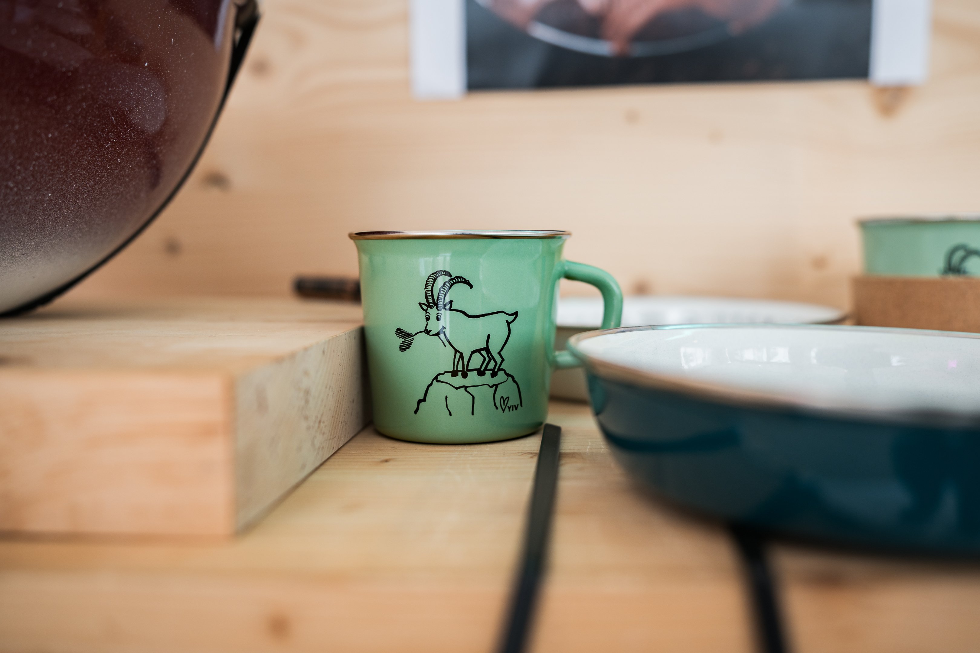 Una tazza verde smaltata e decorata con uno stambecco.