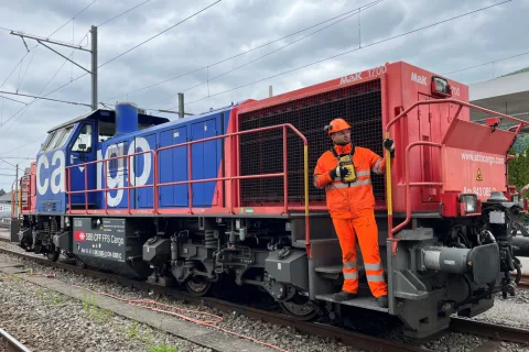 Rangierspezialist Sabit Medi steht auf dem Trittbrett der Rangierlok Am 843 und hält sich an der Haltestange fest.