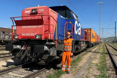 Ein Lokführer steht neben seiner Cargo Lokomotive