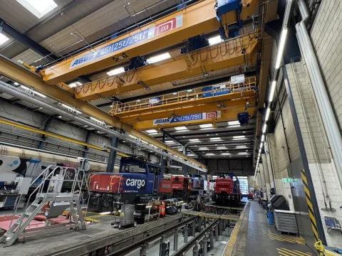 Vue intérieure de l’atelier de loc 2 à Dietikon. Plusieurs locomotives de manœuvre se trouvent sur les voies. On aperçoit la nouvelle grue jaune au-dessus.