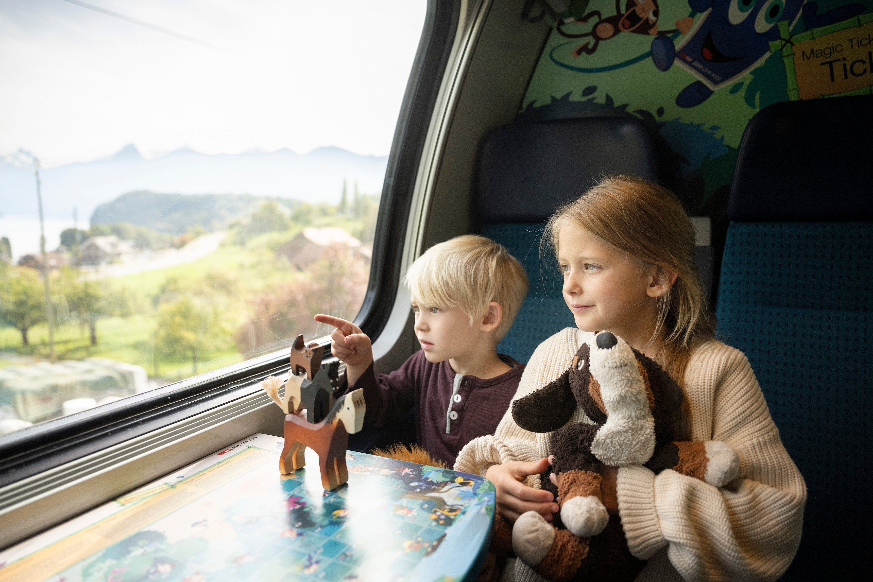 Zwei vergnügte Kinder malen im SBB Familienwagen. Sie sind auf dem Weg in den Europa-Park.