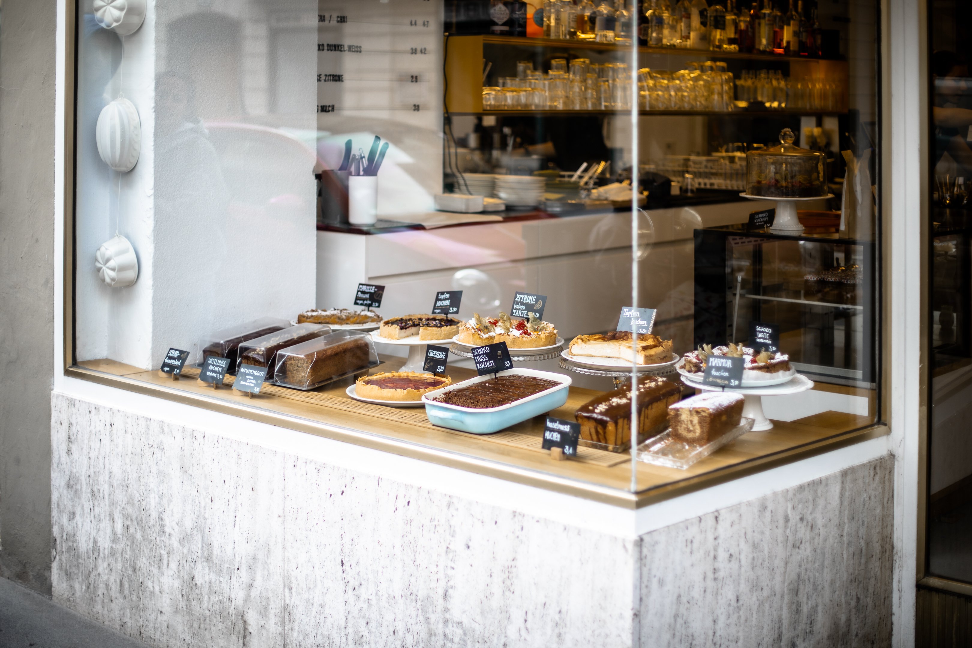 Im Schaufenster des Cafés stehen zwölfverschiedene Kuchen.
