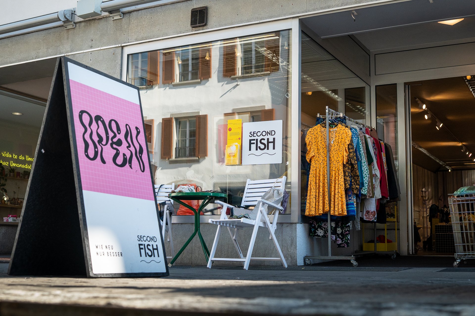 Ein Schild mit der Aufschrift Open steht vor einem Laden mit offener Tür.