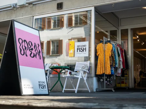 Ein Schild mit der Aufschrift Open steht vor einem Laden mit offener Tür.