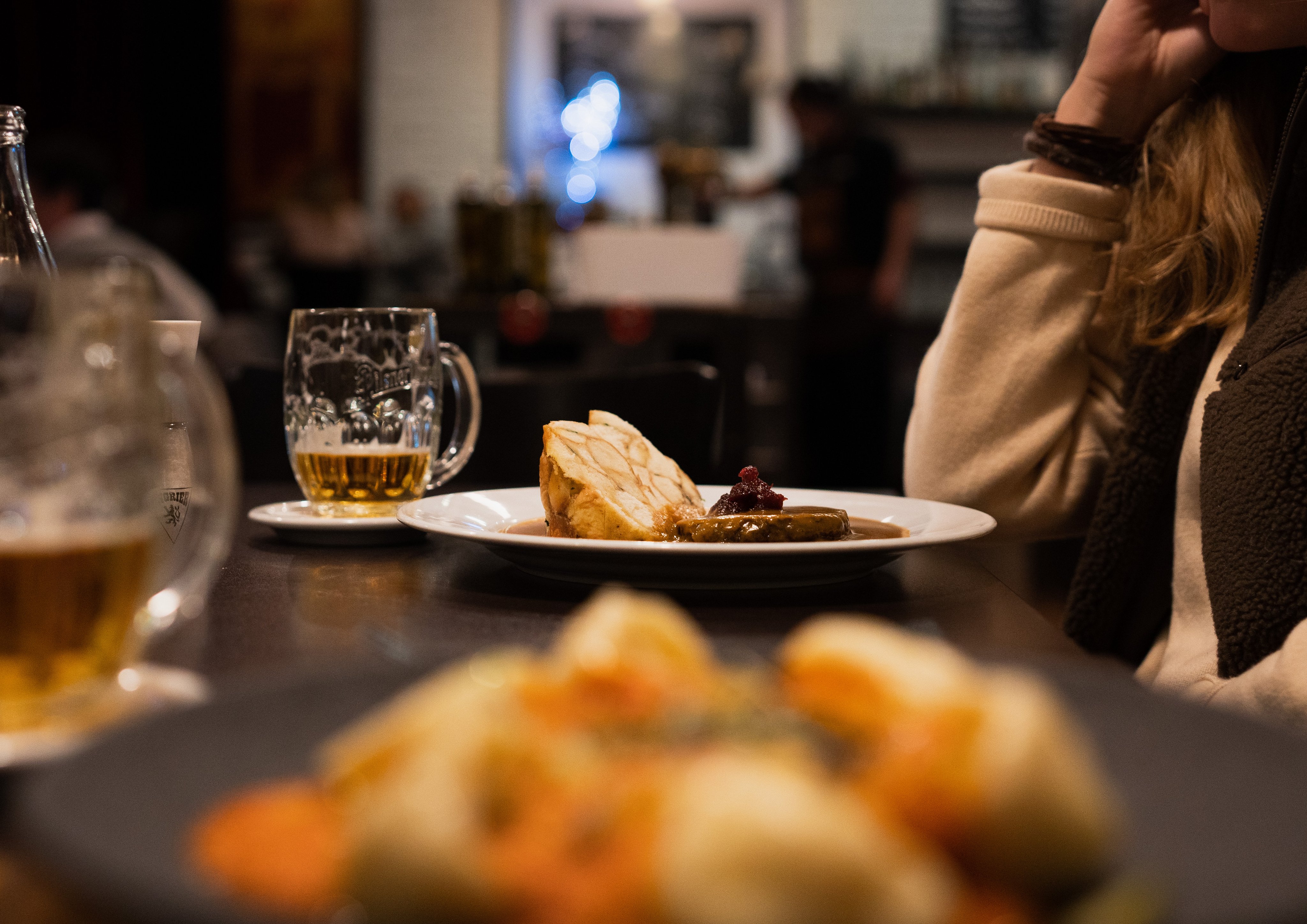 Ein Teller mit Knödel und brauner Sauce mit einem Bier nebendran.