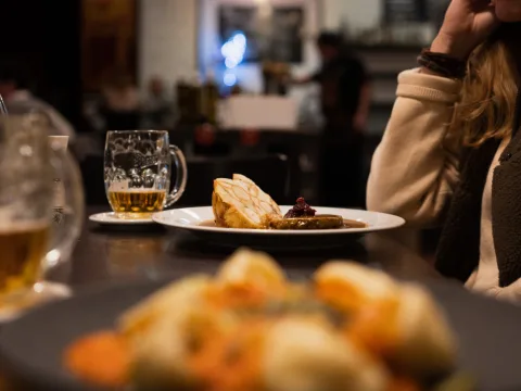 Une assiette de boulettes et de sauce brune avec une bière à côté.