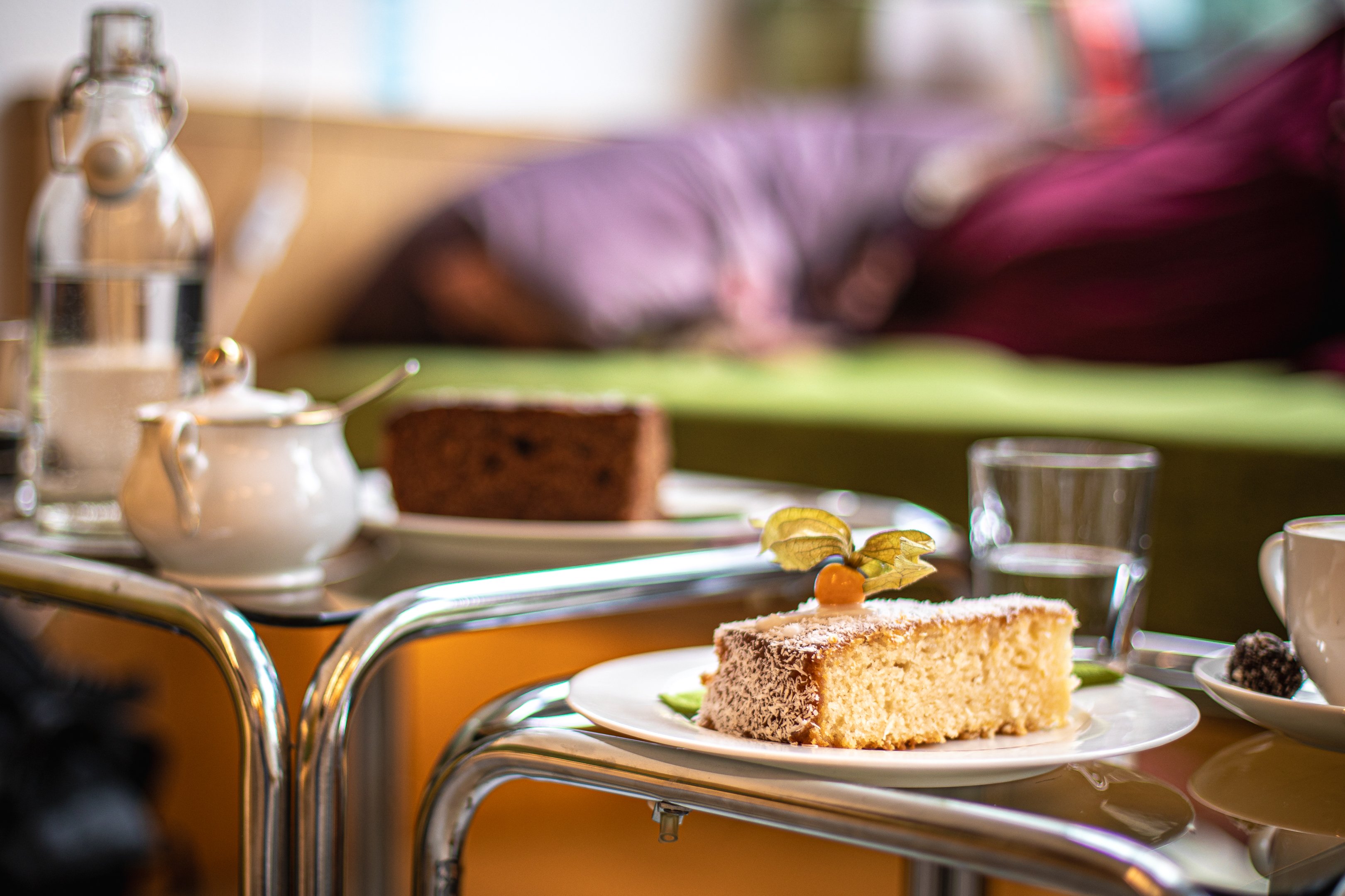 Una fetta di torta di cocco e mele, accanto a dell’acqua e a un caffè.