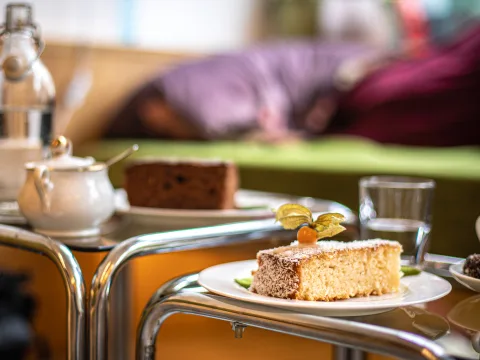 Una fetta di torta di cocco e mele, accanto a dell’acqua e a un caffè.