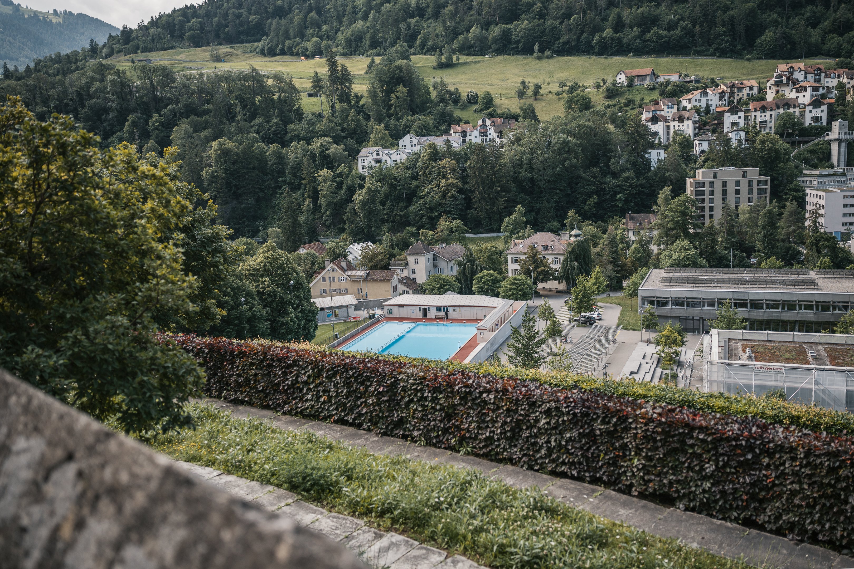 Vista della piscina all’aperto Freibad Sand a Coira, circondata dal prato e dagli alberi.