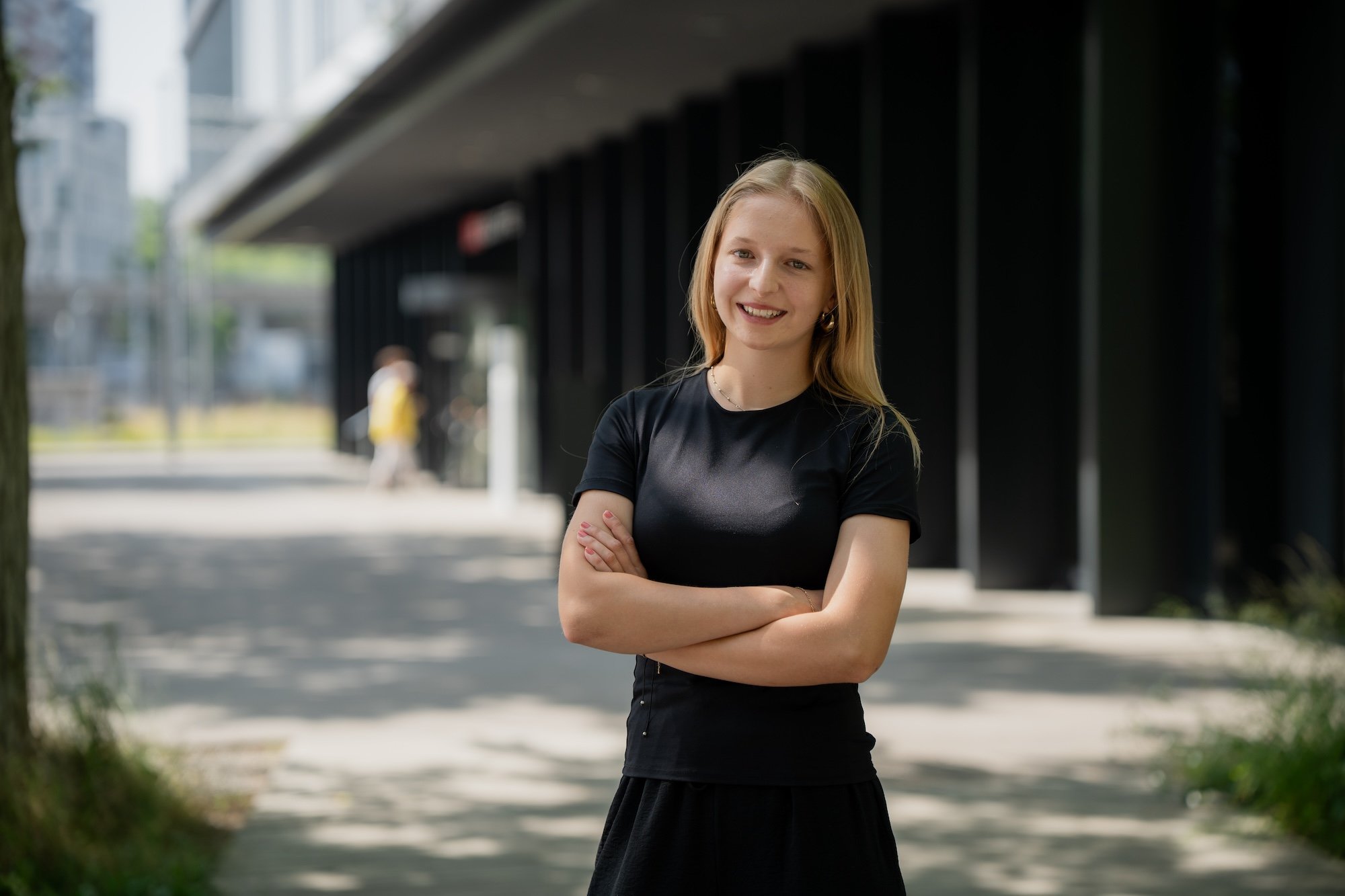 Una donna è in piedi con le braccia incrociate davanti a un edificio.