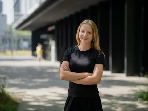 Una donna è in piedi con le braccia incrociate davanti a un edificio.