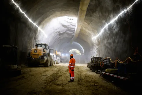 Un ouvrier et des machines dans le tunnel de Gléresse.